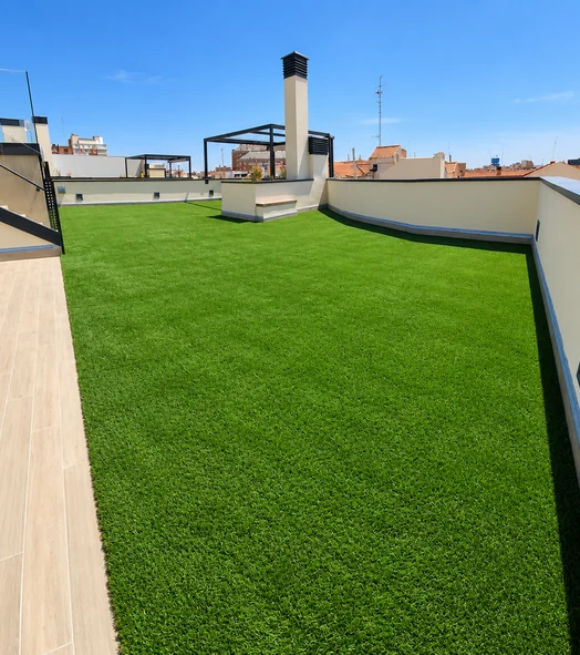 Terraza de ático con césped artificial junto a una tarima