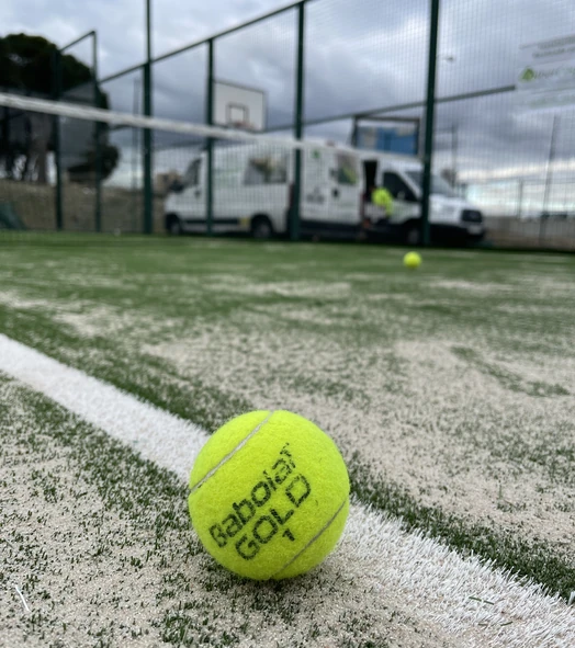 Pelota junto a una línea blanca en una pista de pádel con césped artificial