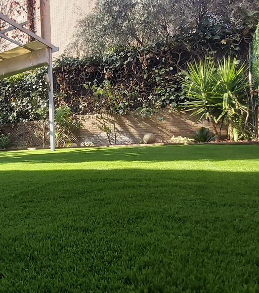 Césped artificial en un jardín con zonas de sol y sombra