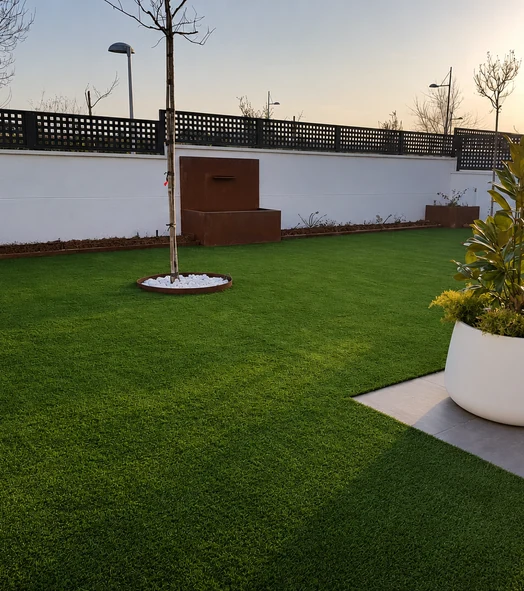 Jardín con césped artificial y árboles sin hojas junto a una valla